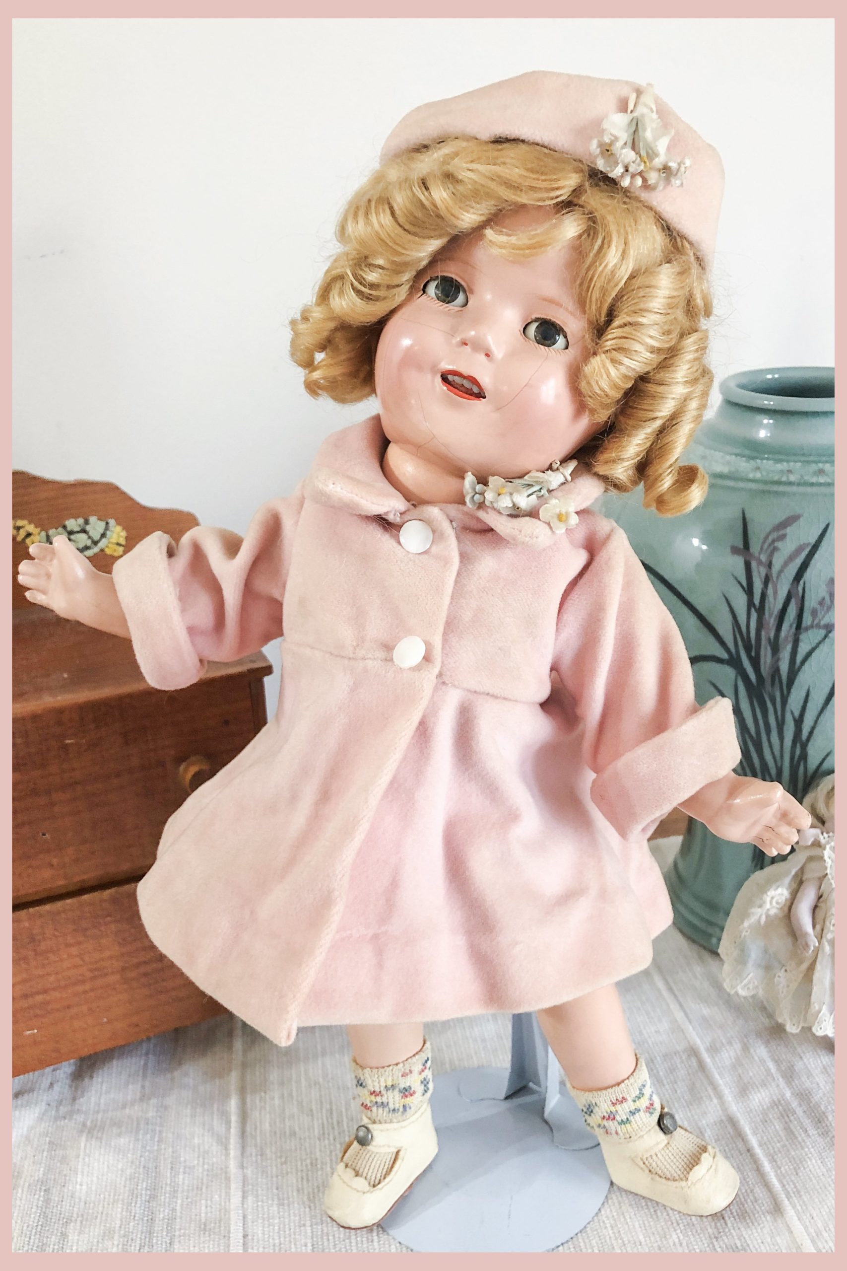 A vintage 1930s composition Shirley Temple Doll wearing a pink coat and hat designed by Molly-'es Outfitters.