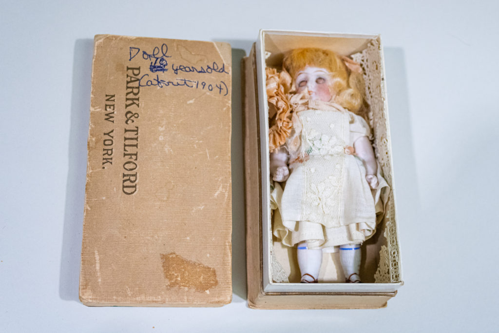 All bisque jointed doll with glass eyes inside an antique Park & Tilford's (New York) cigar box from 1904.