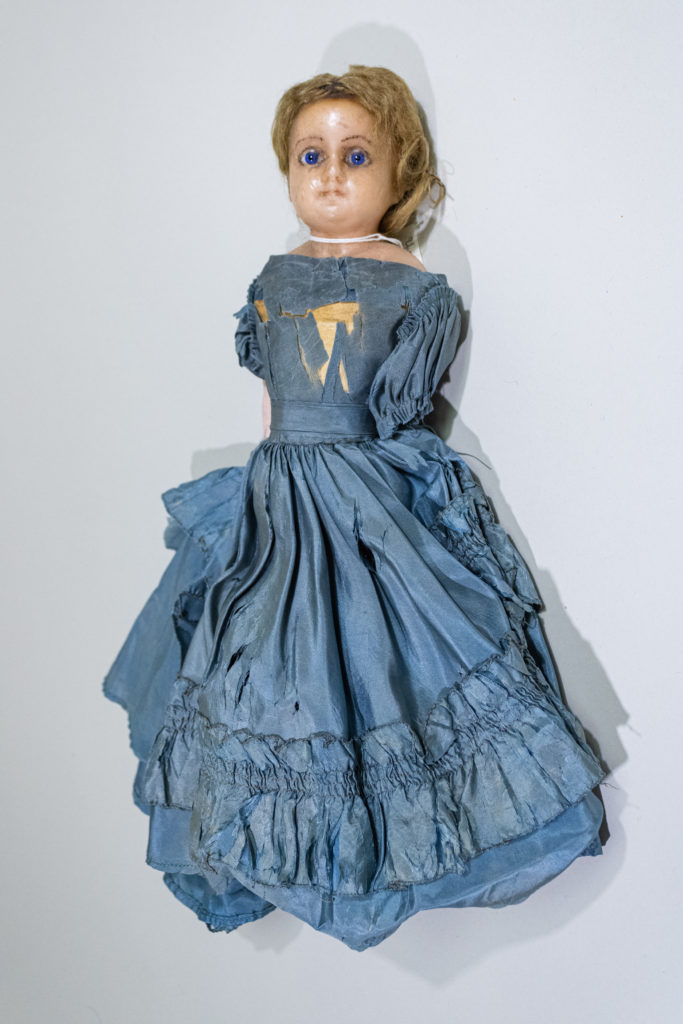 Wax head doll with glass eyes and kid leather body in blue silk dress at the Cape Fear Museum